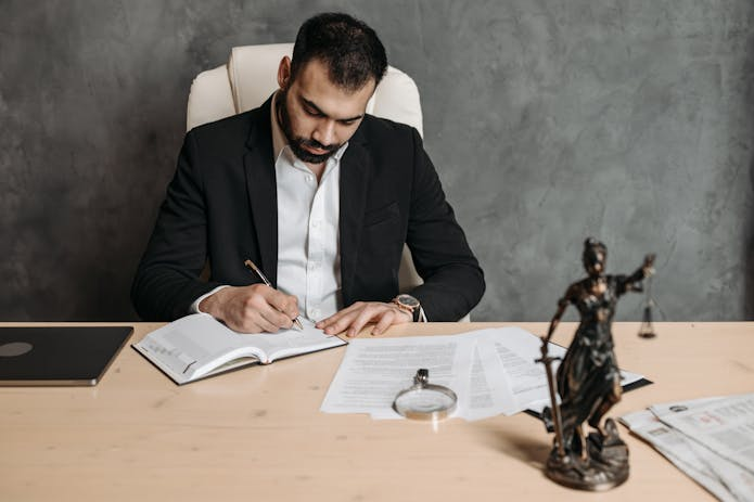 A professional lawyer in a suit diligently writes on a paper, ensuring justice for truck accident victims in San Antonio.