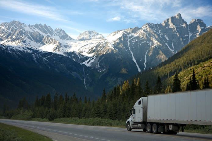 A semi truck driving down a road with mountains in the background. Image may relate to Dallas Truck Accident Injury Attorney services.