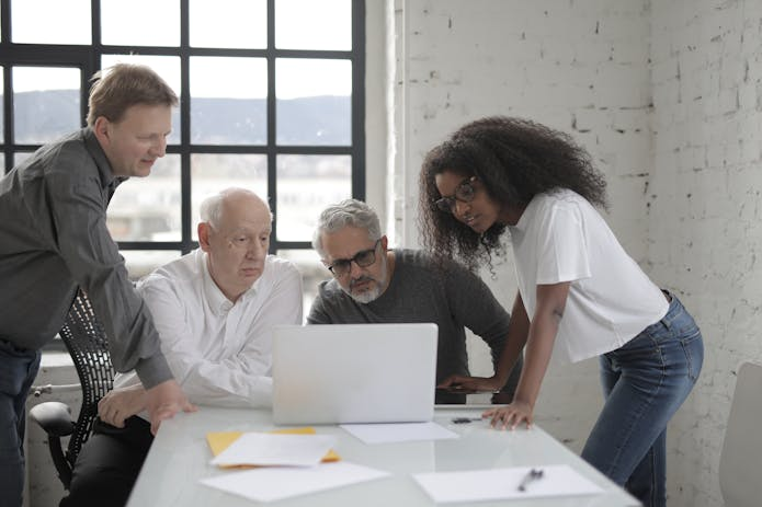 Three people engaged in teamwork on a laptop in an office environment. Seek guidance from a car accident lawyer in Santa Barbara.