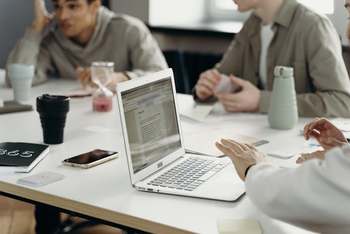 Group of coworkers sitting together with laptops and papers, strategizing Email Marketing Solutions For Small Business.