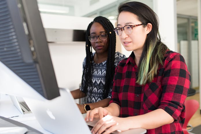 Image of two women in glasses working on a computer, using Online HR Software for Small Businesses.