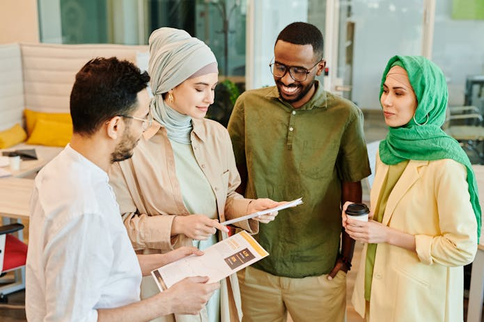 A diverse team in a bustling office engages in a lively discussion. Collaboration and communication are key to success. #Houston18WheelerAttorney