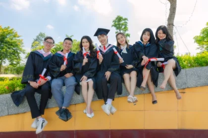 A group of graduates sitting on a wall, celebrating their achievement after earning the most affordable online master's degree in accounting.