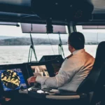 White-shirted man typing on computer on a boat. New Orleans Maritime Injury Attorney.