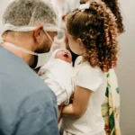 Compassionate birth injury lawyers fighting for your family's rights - an emotional image of a man, a woman, and their baby in a hospital setting.