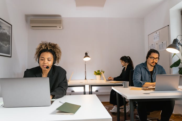 Transform your small business with our email marketing solutions. Image: three people working on laptops in an office.