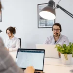 Three people working on laptops in an office, collaborating on tasks while utilizing email marketing solutions for small business.