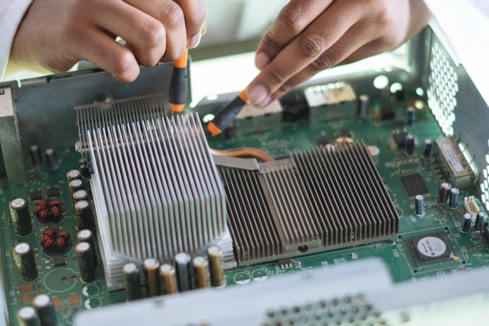 A skilled technician expertly repairs a motherboard using a screwdriver. Trust HVAC Repair Weatherford Tx for top-notch service.