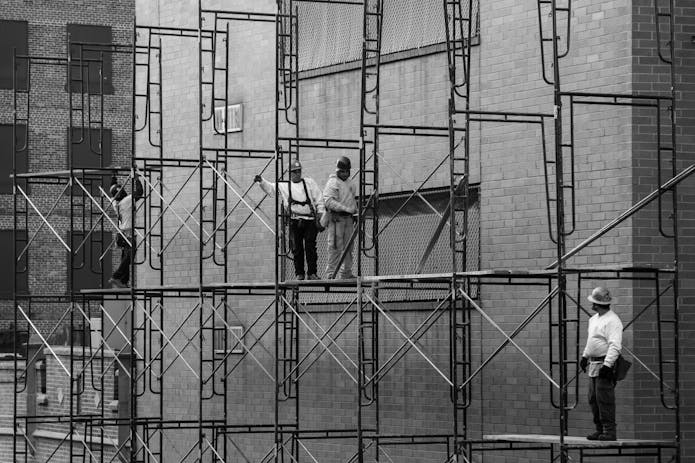 Diligent workers on scaffolding, enhancing a Bronx building. Consult the Bronx Scaffold Accident Lawyer for legal support.