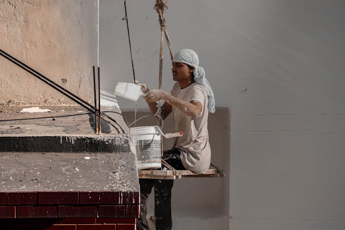 Worker applying cement on building in NYC. Protect your rights with a Construction Injury Lawyer!