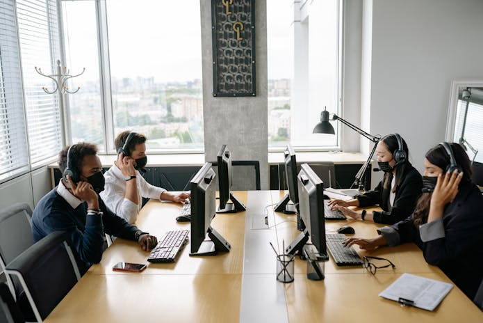 Boost your small business with our email marketing solutions. Image: four people working at a desk in an office.