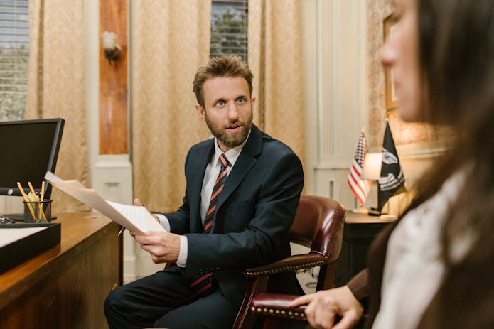 Businessman in suit meeting with woman at desk, looking for pip attorneys nearby.