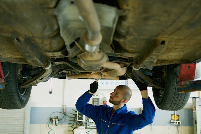 Trustworthy auto claim lawyer nearby, repairing a car in blue attire.