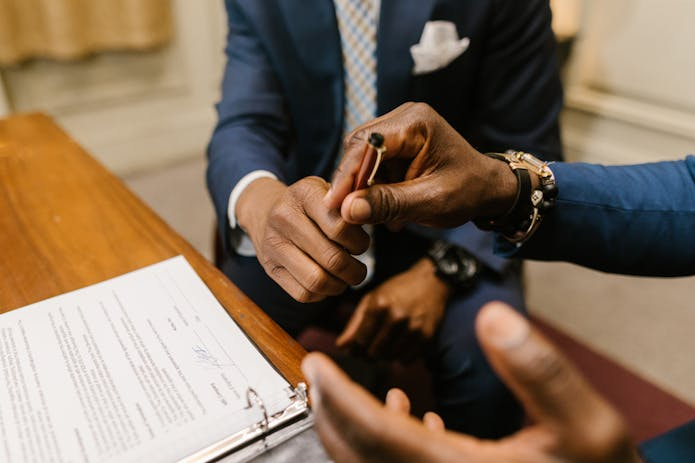 Two professionals in suits signing legal documents at a desk. Expert attorneys providing pip services near me.