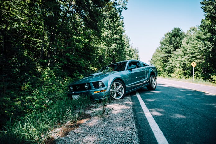 Blue Mustang parked on road. Visit nearby truck accident injury law firm for legal help.