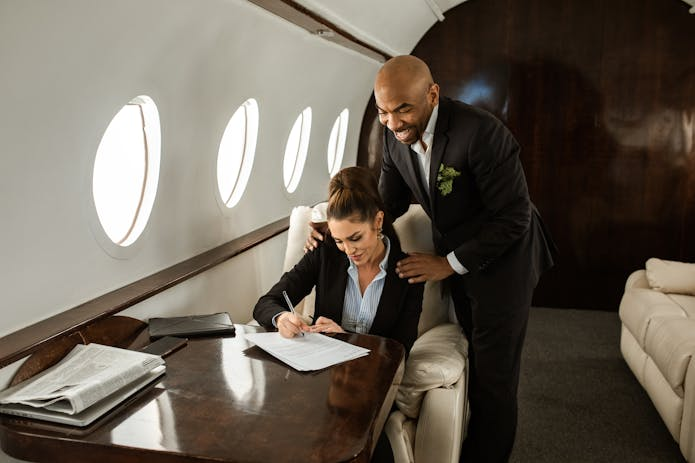 A man and woman in business attire sitting in an airplane. Image may relate to 'pip attorneys near me'.