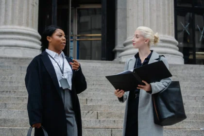 Two professional women in business attire engaged in a conversation on steps. Image may relate to a Riverside slip and fall lawyer.