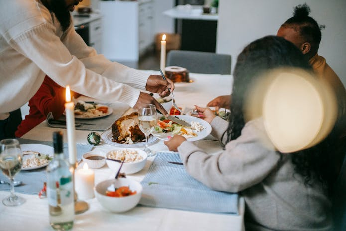 A family sits at a table with food and candles, dining at Olive Garden Babbo Restaurant.