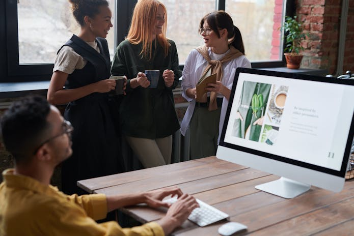 Three individuals standing around a computer screen, learning about the history of computers.