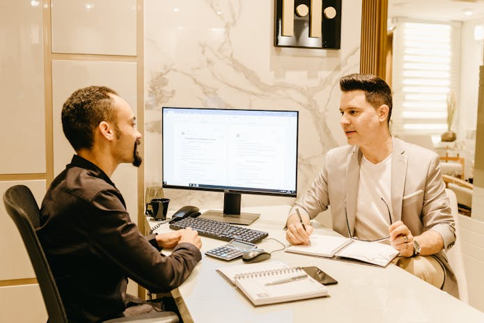 Two men sitting at a desk, engrossed in their work on a computer, as part of the History of Computers.