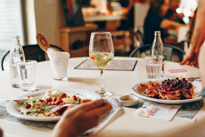 Two people enjoying a meal at Olive Garden L and B Spumoni Restaurant, with plates of food and drinks on the table.