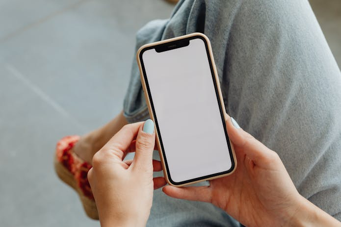 Woman excitedly holds a smartphone with a blank screen, ready to unveil the features of iOS 18.