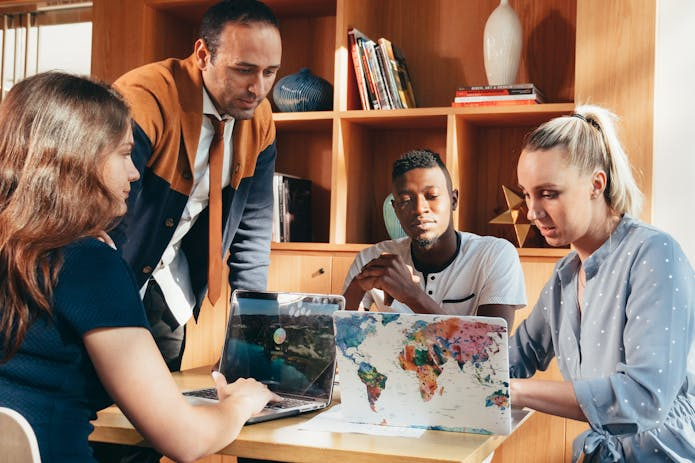 Office scene with business people collaborating, showcasing a Dell XPS 17 laptop among their work materials.