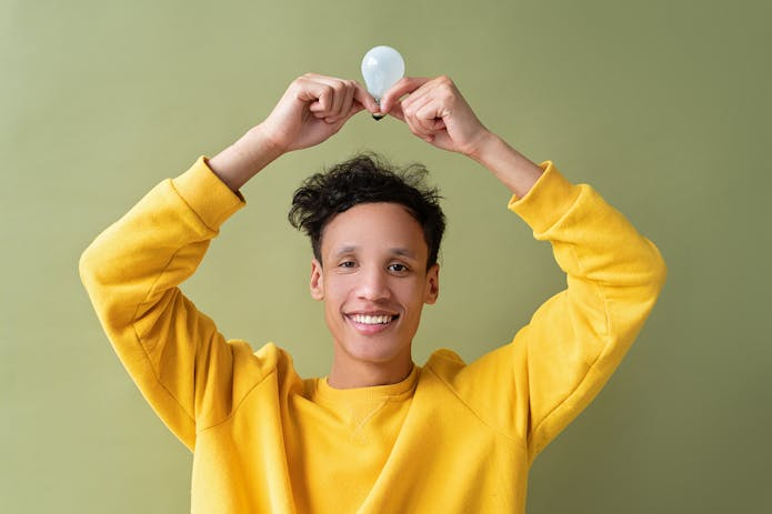  An innovative young man displaying an LED light bulb, symbolizing eco-friendly lighting solutions.