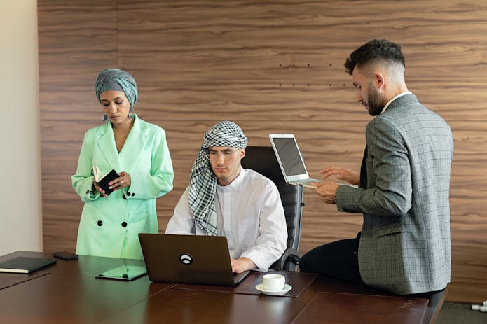 Three professionals in business attire seated at a table, each using an HP 17 laptop for a collaborative meeting.