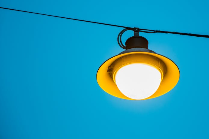 Yellow LED street light against blue sky.