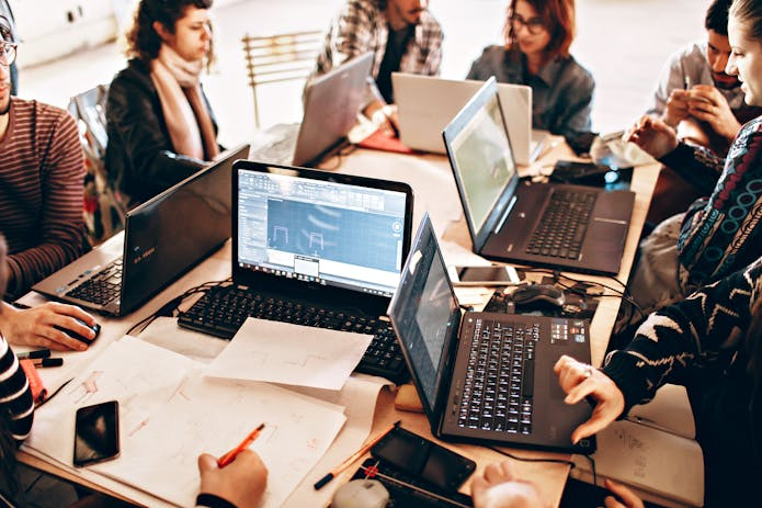 Several people seated at a table, engaged with their Origin EON17-X laptops, focused on a group project.