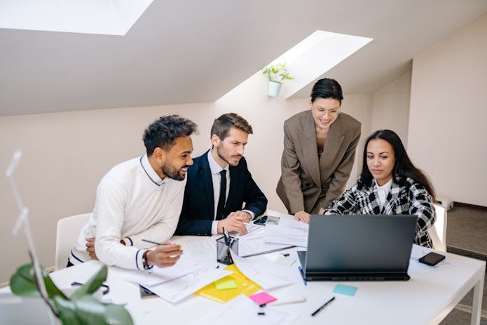 Business professionals collaborating in an office setting, with an Alienware m17 R5 17 laptop prominently displayed on the table.