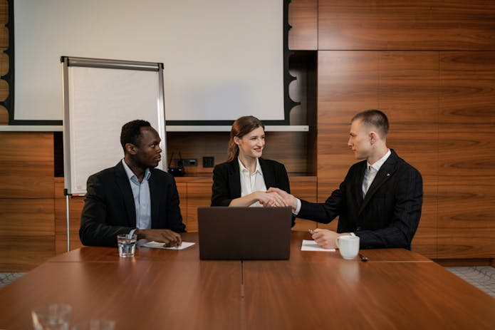 Business partners shaking hands in a meeting room, highlighting the importance of agreements in professional relationships.