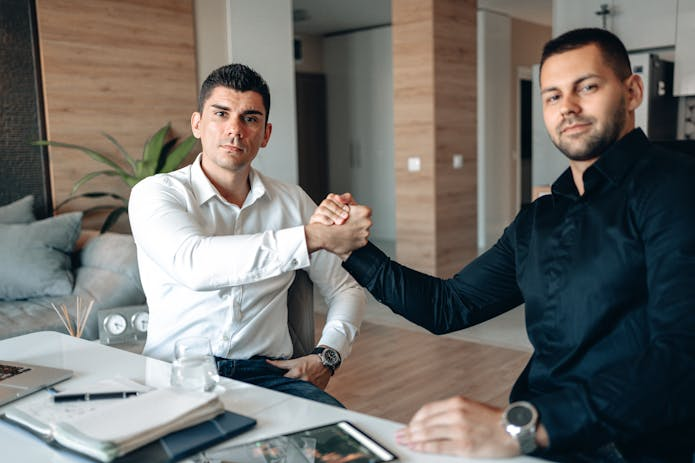 Two men shaking hands at a table in an office, indicating a mutual agreement in personal injury legal representation.