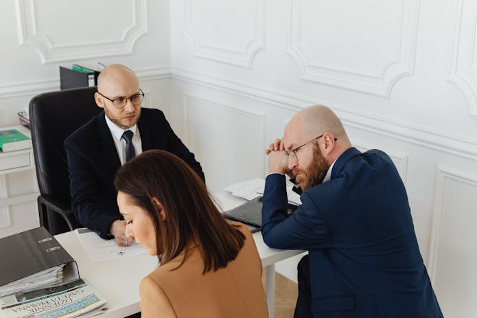 A meeting of three business people at a table in an office, highlighting teamwork and collaboration.